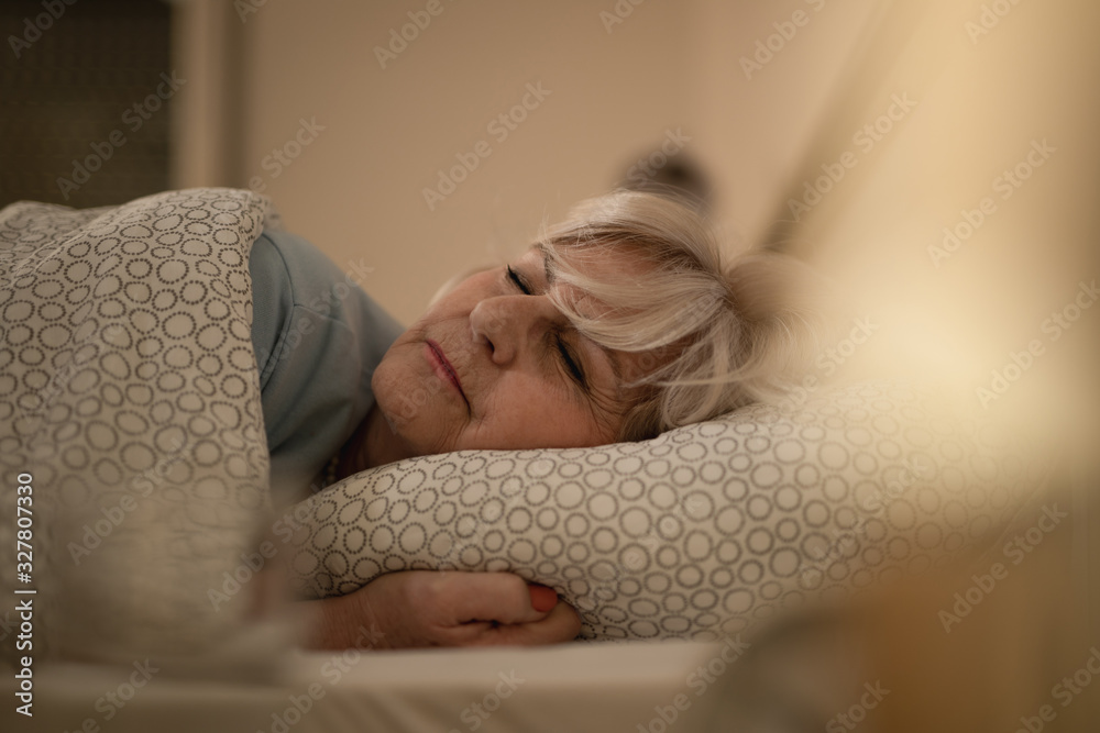 Senior woman sleeping on bed at night. - obrazy, fototapety, plakaty 