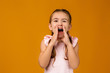 © producer - child calling someone. cute little girl shouting and holding her hand near her mouth on studio yellow background