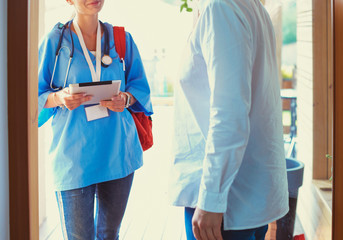 Female doctor with clipboard during home visit while entering house