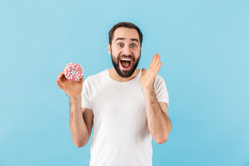 Canvas Print - Excited man isolated over blue wall holding donut.