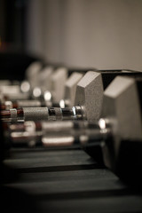 Close up many metal dumbbells on rack in sport fitness center. Weight Training Equipment concept. Sport and fitness, exercise design.