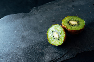 Fresh kiwi match in two halves on slate board. natural light. healthy food concept