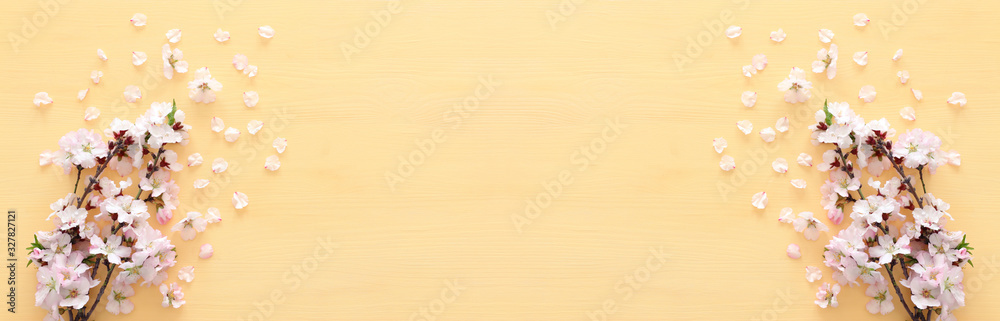 photo of spring white cherry blossom tree on pastel yellow wooden background. View from above, flat lay - obrazy, fototapety, plakaty 