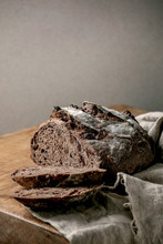 Sliced Fresh Baked Artisan Round Homemade Chocolate And Cranberries Rye Bread On Linen Cloth Over Wooden Kitchen Table. Copy Space
