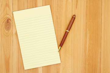 Wall Mural - Yellow legal lined notepad paper with a pen on pine wood desk