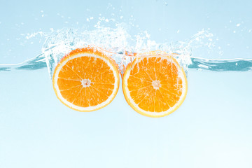 Aufkleber - Yummy juicy orange cut in half and water splashes on blue background
