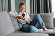 © Drobot Dean - Image of smiling nice woman using cellphone while sitting on sofa