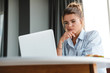 © Drobot Dean - Image of serious nice woman working with laptop while sitting at table