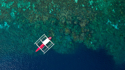 Wall Mural - Aerial top down view of boat moving in open sea with clear and turquoise water on over coral reef,  Boat left the tropical lagoon, Moalboal, Oslob, Cebu Island, Philippines.