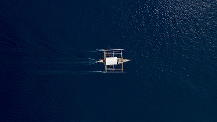 Wall Mural - Aerial top down view of boat moving in open sea with clear and turquoise water on over coral reef,  Boat left the tropical lagoon, Moalboal, Oslob, Cebu Island, Philippines.