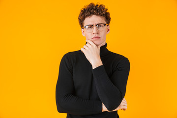 Poster - Image of young puzzled man in eyeglasses poising and looking at camera