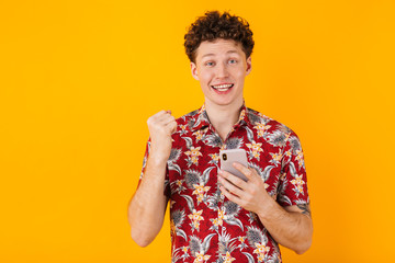 Poster - Image of young delighted man using cellphone and making winner gesture