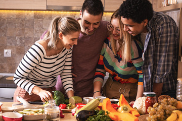 Group of friends preparing vegetarian meal.They preparing food and making fun in the kitchen.