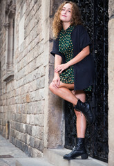 Young sexy woman in dress standing near the stone wall  in historical center