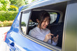 © comzeal - Asian teenager woman using a smartphone in back seat of car, Passengers use an app to order a ride and Peer-to-peer ride sharing concept