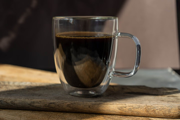 black coffee in transparent big mug on black background