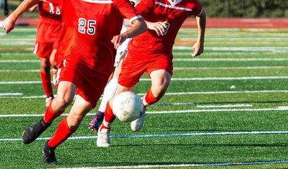 Soccer players in red uniforms chasing the ball during game