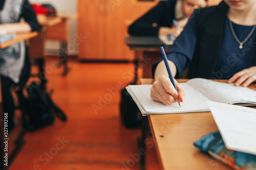 The student writes in a notebook in the classroom, test, exam, writes the text