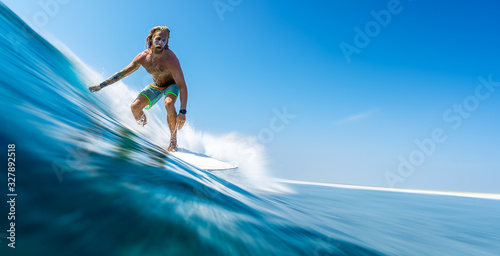 Fotomural Young man surfer with long hair surfs the fast and perfect ocean wave in Maldive