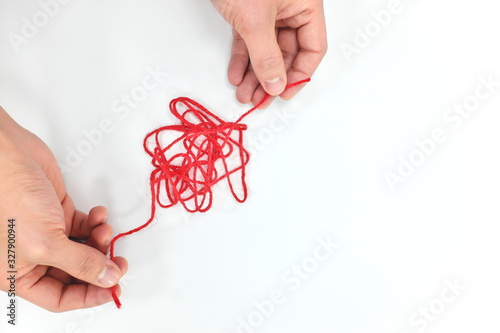 Cuadros en Lienzo Hands fixing a tangled red yarn in white background