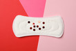 Sanitary pad with glitter on multicolor background, top view