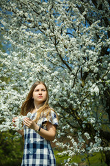 Wall Mural - beautiful girl in a dress walking in the spring forest where the trees bloom