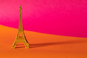 Miniature yellow Eiffel Tower on colorful background, travel and tourism concept. 