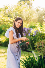 Pretty Young Woman Watering Plants In Summer Garden