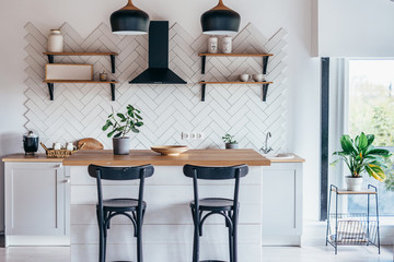 Modern new light interior of kitchen with white furniture and dining table.