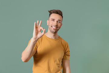 Happy man showing OK gesture on color background