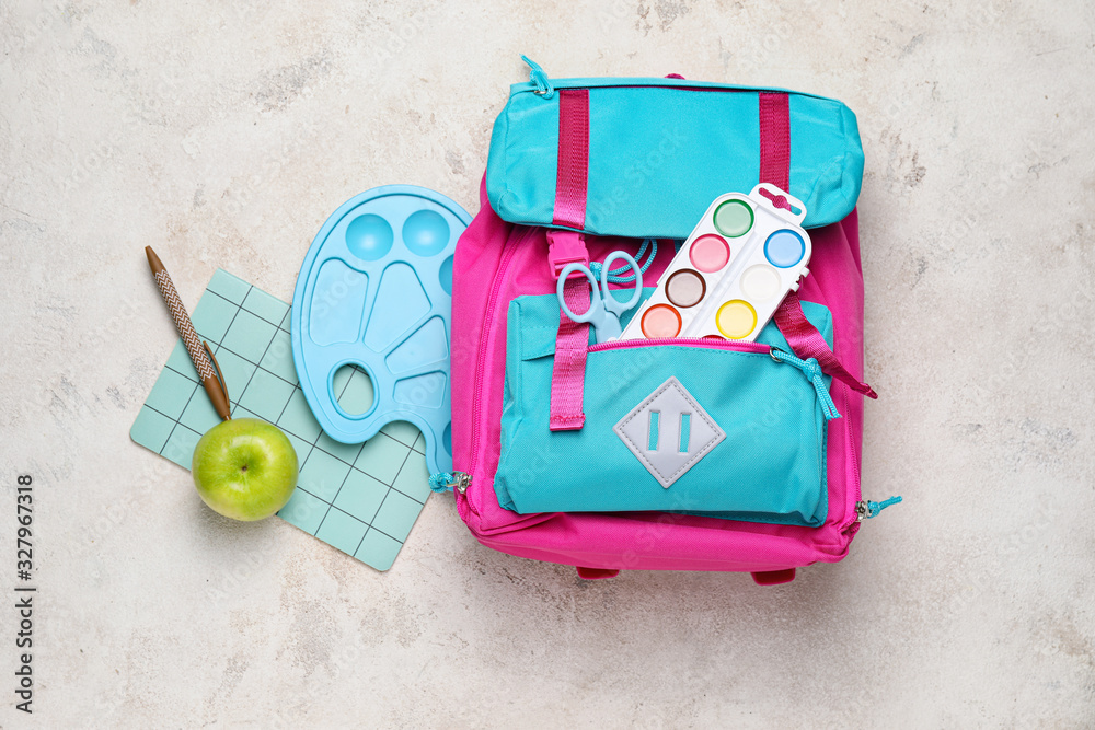 School backpack and stationery on light background
