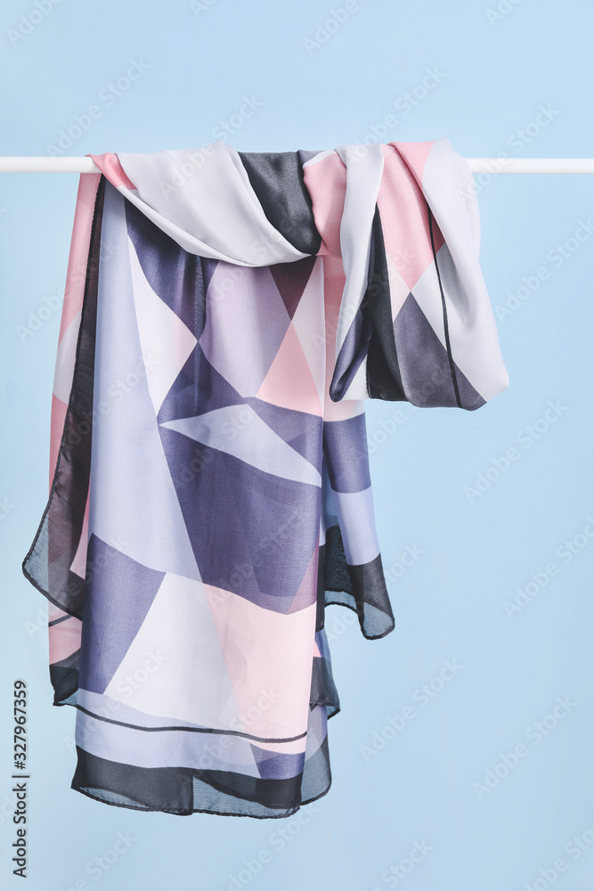 Beautiful scarf hanging on rack against color background