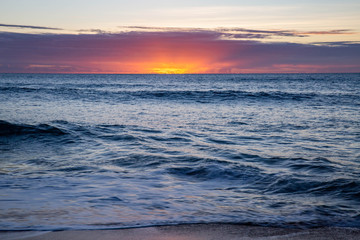 calming ocean waves over pink hawaiian sunset