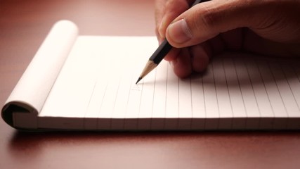 Poster - Male hand with pencil writing on notebook. Male working in home office