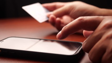 Poster - Closeup male hands holding credit card and using mobile smart phone for online shopping