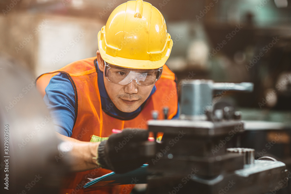 Asian Chinese engineer worker wearing safety suit helmet and eyes protection glasses focus at work inspection and checking production process on factory. - obrazy, fototapety, plakaty 