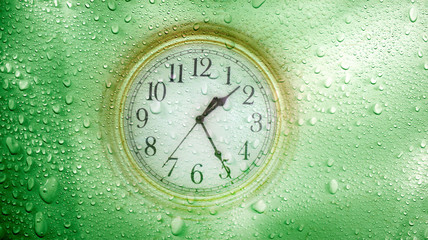 Wall Mural - close up abstract raindrops and clock face over green background