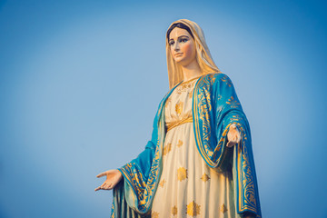 Wall Mural - Close-up of the blessed Virgin Mary statue figure. Catholic praying for our lady - The Virgin Mary. Blue sky copy space on background.