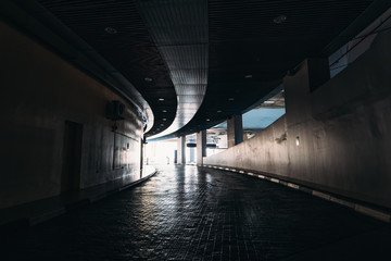 Exit to light from dark underground tunnel in car parking in mall.