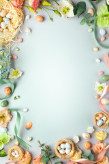 Poster - Happy Easter concept with easter eggs in nest and spring flowers. Easter background with copy space. Flat lay.