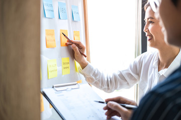 Poster - Two creative Business people meeting and planning use post it notes sticky note on board to share idea, Analysis data charts and graph with teamwork strategy brainstorming