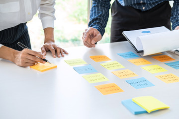 Poster - Two creative business people meeting and planning use post it notes sticky note on desk to share idea, Analysis data chart and graph with teamwork strategy brainstorming in office