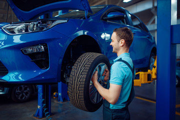 Wall Mural - Worker removes wheel from vehicle, car service