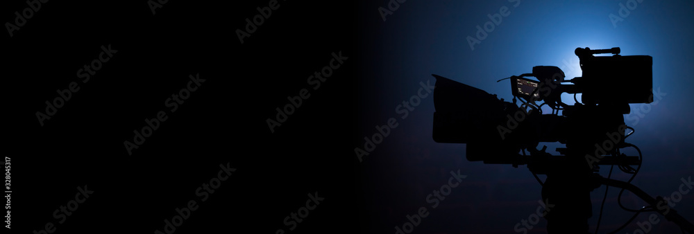 video camera silhouette in the dark banner with blue light, movie or television background - obrazy, fototapety, plakaty 