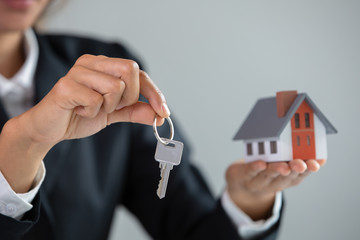 Your new house, real estate agent holding house key to his client after signing contract agreement in office,concept for real estate, renting property