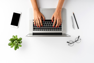 Female hands using laptop on white background with accessories. Office desktop. Top view
