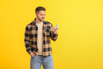 Wall Mural - Young man with mobile phone on color background