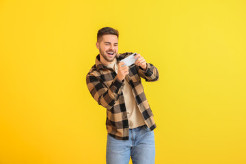 Wall Mural - Happy man with mobile phone on color background