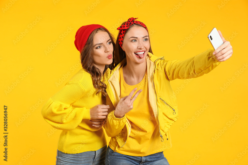 Young women taking selfie on color background
