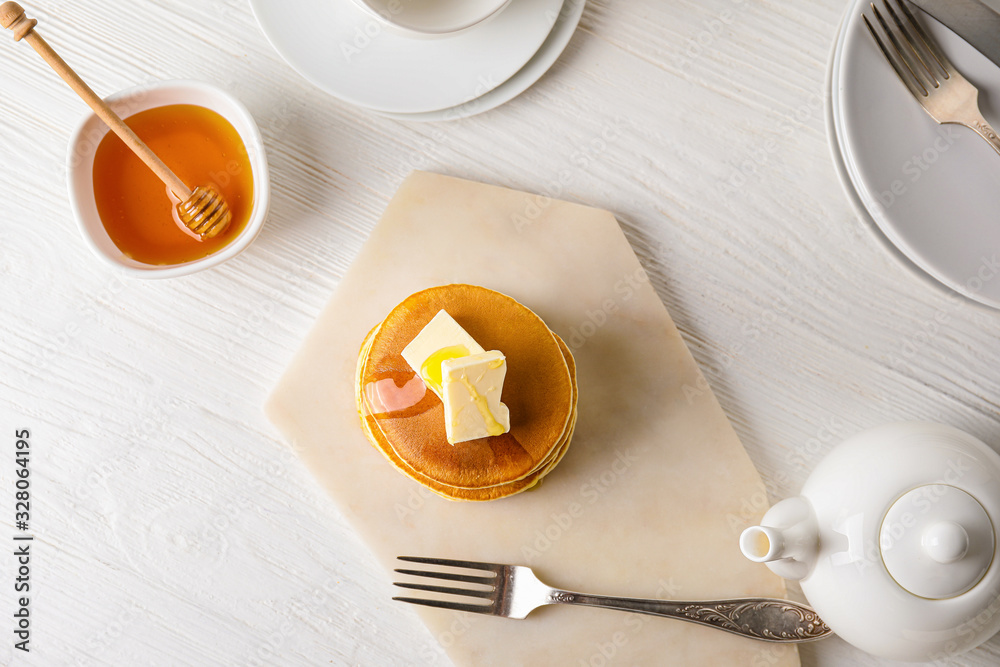 Tasty pancakes with honey and butter on table